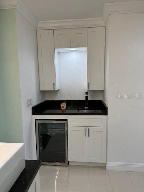 kitchen featuring ornamental molding, sink, light tile patterned flooring, beverage cooler, and white cabinetry