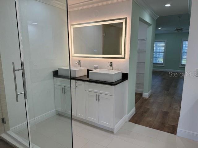 bathroom with a shower with door, wood-type flooring, ornamental molding, vanity, and ceiling fan