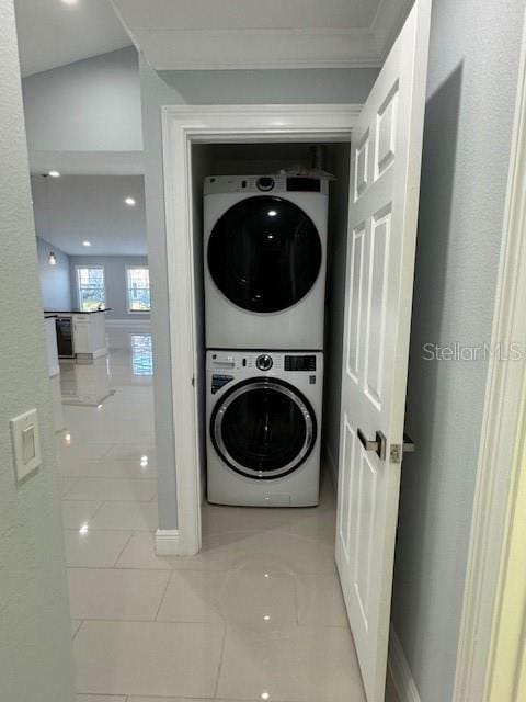 washroom featuring ornamental molding and stacked washing maching and dryer