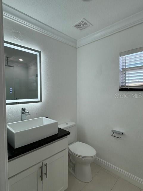 bathroom with toilet, tile patterned floors, walk in shower, vanity, and crown molding