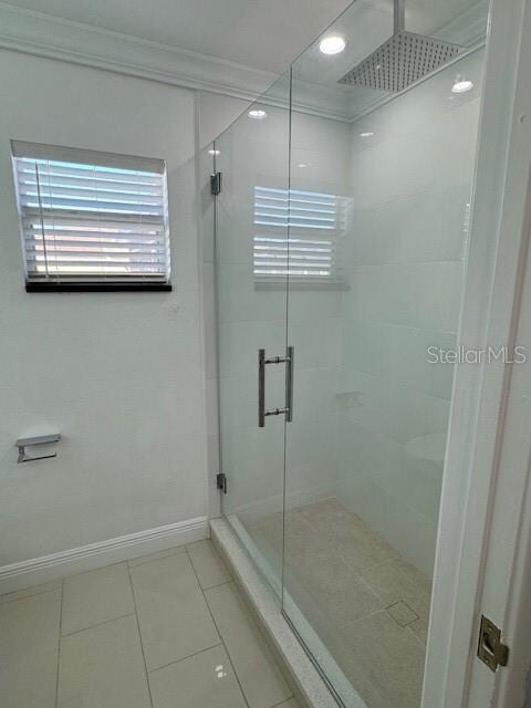 bathroom with a shower with door and tile patterned floors