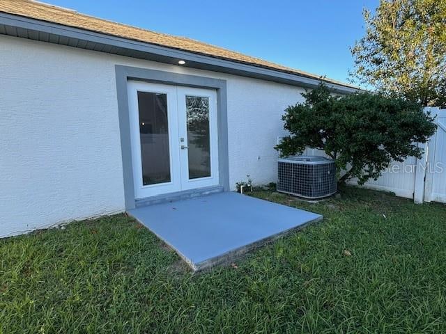 entrance to property with french doors, a yard, and central air condition unit