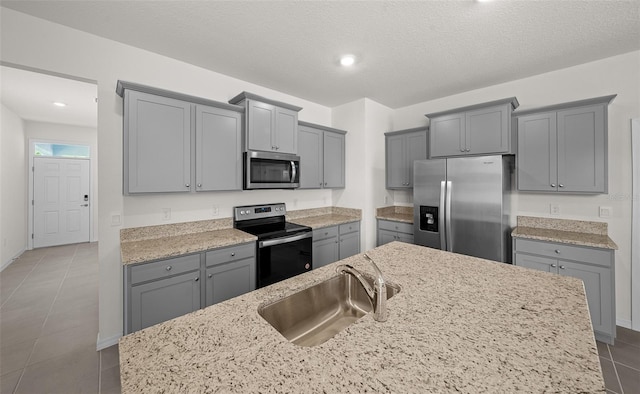 kitchen featuring a textured ceiling, stainless steel appliances, gray cabinetry, and sink