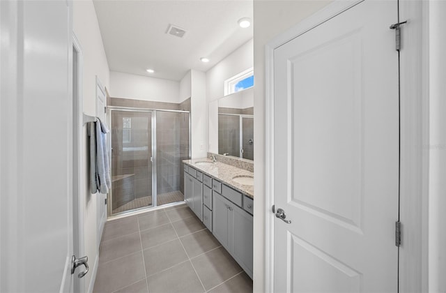 bathroom with a shower with shower door, vanity, and tile patterned floors