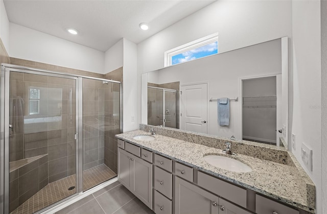 bathroom with walk in shower, vanity, and tile patterned flooring