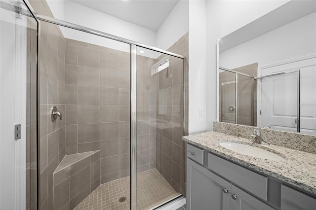 bathroom featuring a shower with door and vanity