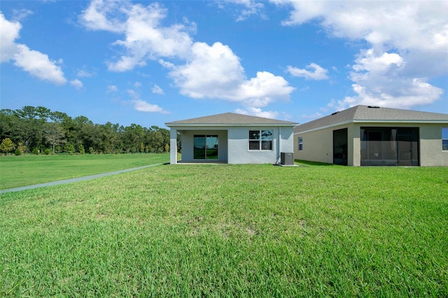 rear view of house featuring central AC unit, a lawn, and a sunroom