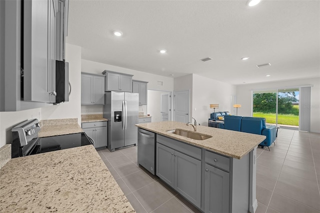 kitchen featuring stainless steel appliances, sink, gray cabinets, a kitchen island with sink, and light tile patterned flooring