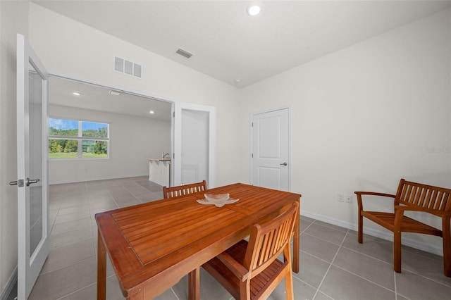 dining area with light tile patterned floors and vaulted ceiling