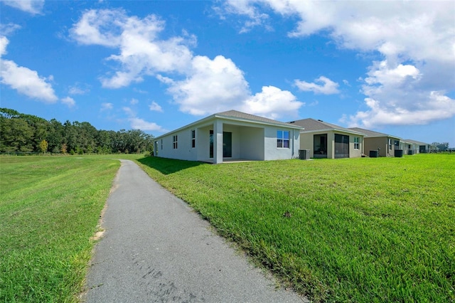 view of front of property featuring a front lawn, central air condition unit, and a sunroom