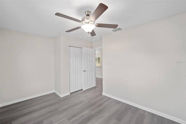 unfurnished bedroom featuring ceiling fan, a closet, and wood-type flooring