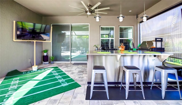 kitchen featuring ceiling fan, a healthy amount of sunlight, and a breakfast bar