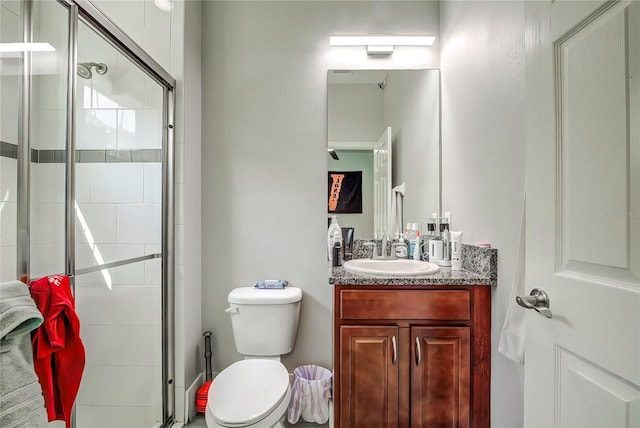 bathroom with vanity, a shower with shower door, and toilet