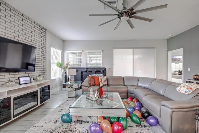 living room with ceiling fan, light hardwood / wood-style flooring, and a large fireplace