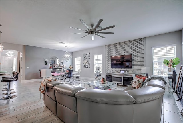 living room with light hardwood / wood-style flooring, ceiling fan with notable chandelier, and a wealth of natural light