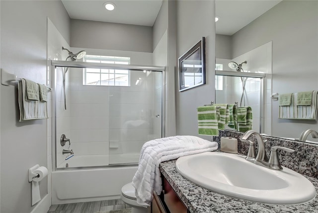 full bathroom with vanity, bath / shower combo with glass door, a healthy amount of sunlight, and toilet