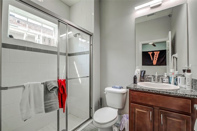 bathroom featuring vanity, a shower with shower door, and toilet