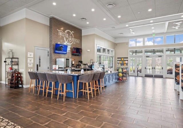 interior space featuring ornamental molding, a towering ceiling, and light stone countertops