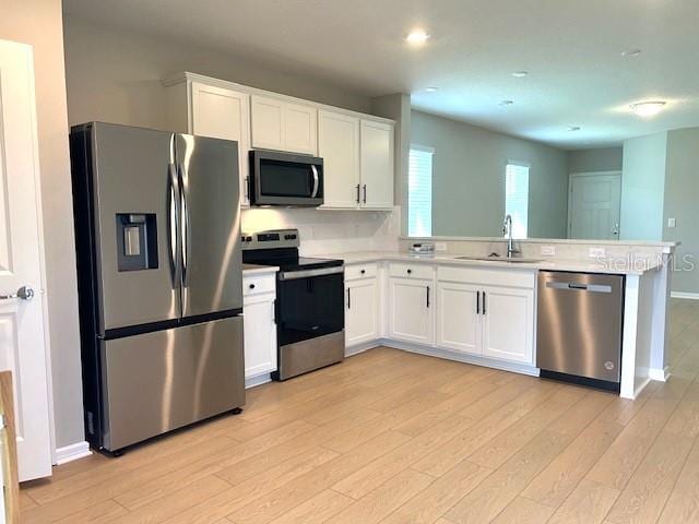 kitchen featuring white cabinets, light hardwood / wood-style floors, appliances with stainless steel finishes, and sink