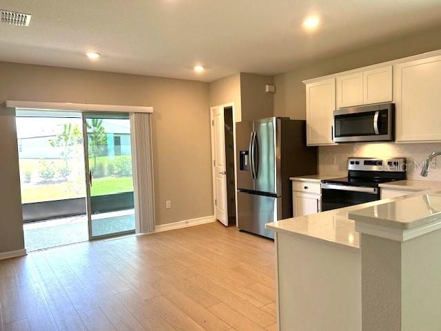 kitchen with light hardwood / wood-style flooring, stainless steel appliances, and white cabinets