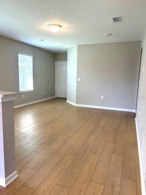 unfurnished room featuring a textured ceiling and light wood-type flooring