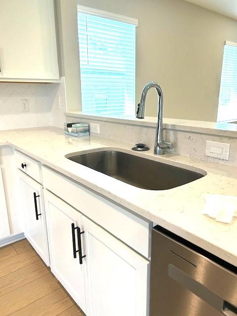 kitchen featuring light stone countertops, a healthy amount of sunlight, and stainless steel dishwasher