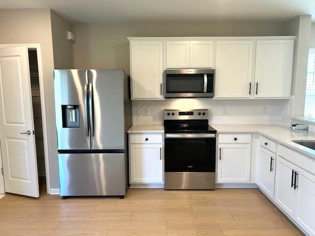 kitchen featuring stainless steel appliances, light wood-type flooring, and white cabinetry