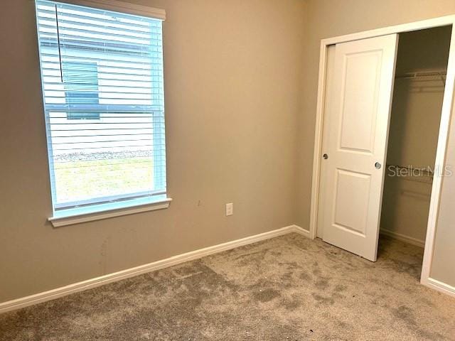 unfurnished bedroom with a closet, carpet flooring, and multiple windows