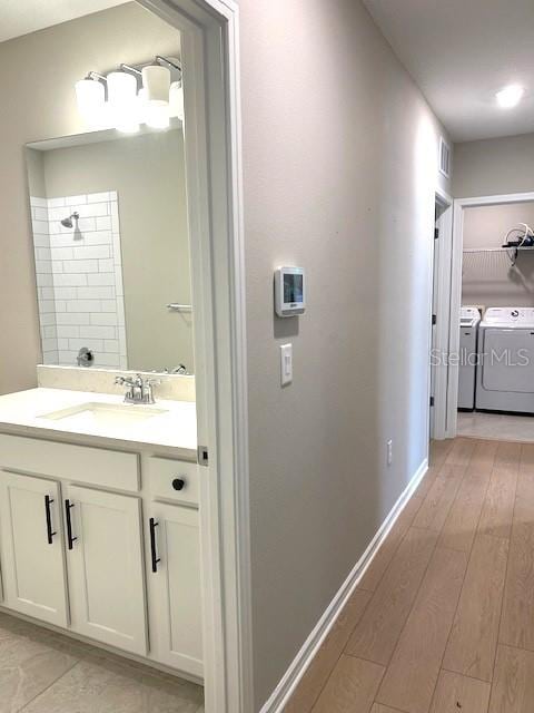 bathroom featuring vanity, independent washer and dryer, hardwood / wood-style floors, and a shower