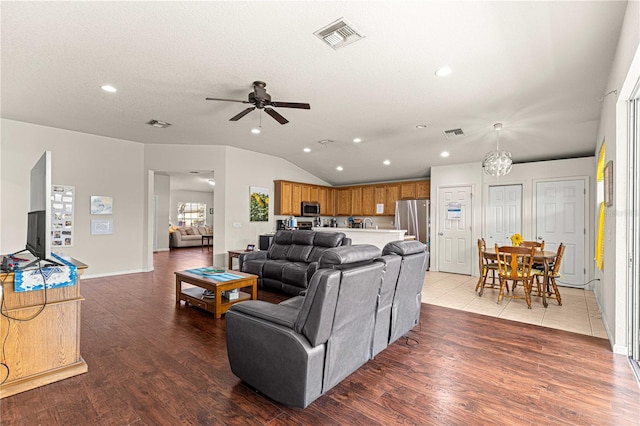 living room with ceiling fan with notable chandelier, lofted ceiling, a textured ceiling, and hardwood / wood-style floors