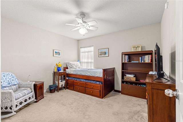 bedroom featuring a textured ceiling, light carpet, and ceiling fan