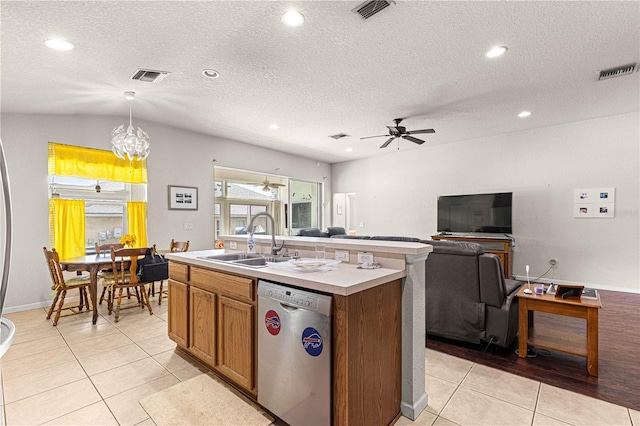 kitchen with hanging light fixtures, an island with sink, ceiling fan with notable chandelier, stainless steel dishwasher, and sink