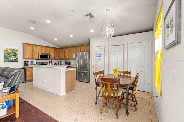 kitchen featuring stainless steel appliances, lofted ceiling, decorative light fixtures, a kitchen island with sink, and a notable chandelier