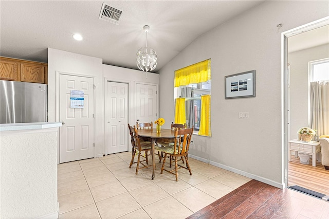 dining area with an inviting chandelier, lofted ceiling, and light hardwood / wood-style floors