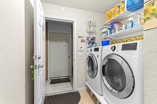 clothes washing area featuring a textured ceiling, light tile patterned floors, and washing machine and dryer