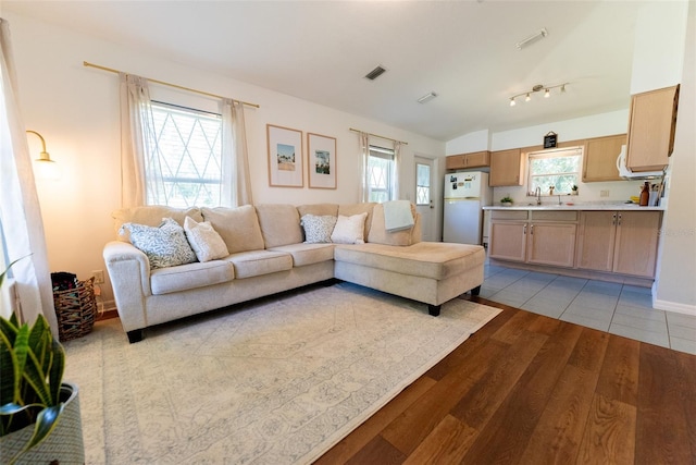 living room with light hardwood / wood-style flooring, sink, and a healthy amount of sunlight