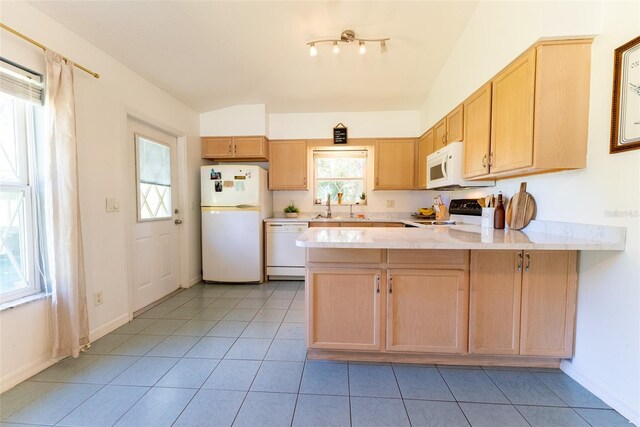 kitchen featuring light tile patterned flooring, white appliances, kitchen peninsula, light brown cabinetry, and sink