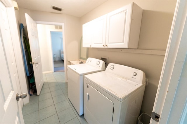 laundry room featuring cabinets, washing machine and clothes dryer, and light tile patterned flooring