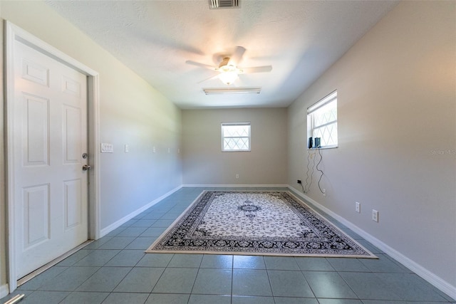 foyer entrance with ceiling fan, light tile patterned flooring, and a textured ceiling