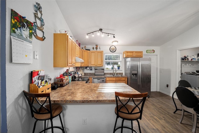 kitchen with sink, stainless steel appliances, dark hardwood / wood-style floors, a breakfast bar, and washer and dryer