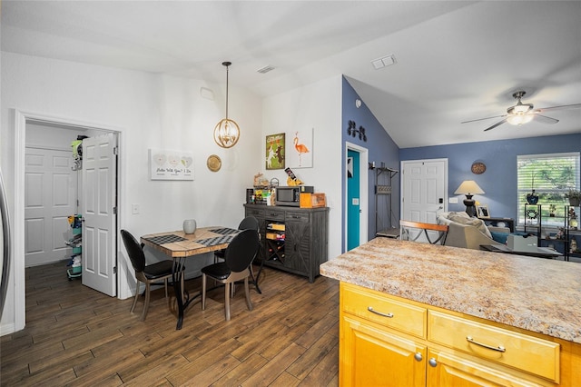 kitchen featuring vaulted ceiling, light stone counters, ceiling fan, decorative light fixtures, and dark hardwood / wood-style floors