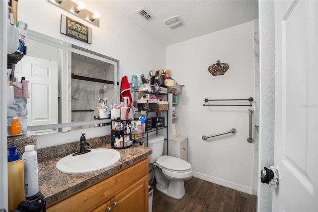 bathroom with a textured ceiling, hardwood / wood-style flooring, a shower with shower door, vanity, and toilet