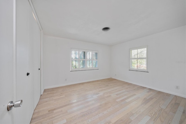 spare room featuring light wood finished floors, baseboards, and visible vents