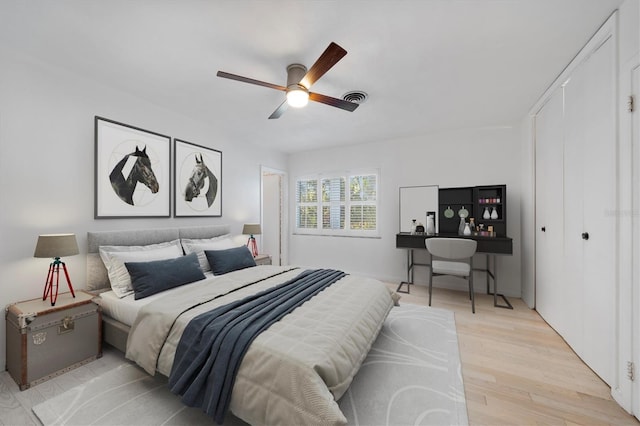 bedroom with light wood-type flooring, a closet, visible vents, and ceiling fan