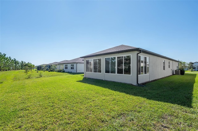 rear view of house featuring a lawn and central AC unit