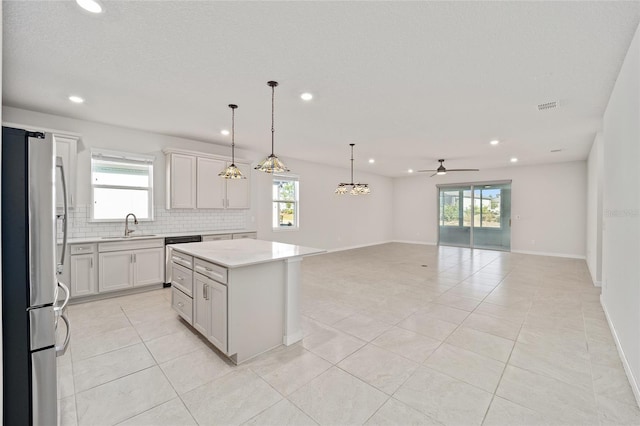 kitchen featuring hanging light fixtures, ceiling fan, decorative backsplash, appliances with stainless steel finishes, and a kitchen island