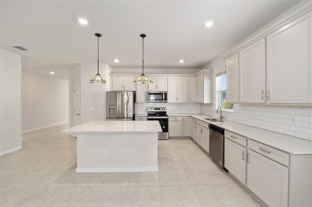 kitchen featuring stainless steel appliances, sink, white cabinets, a center island, and hanging light fixtures