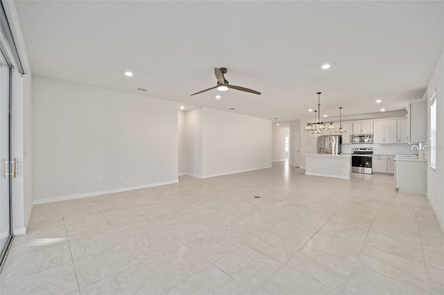 unfurnished living room featuring light tile patterned flooring, ceiling fan, and sink