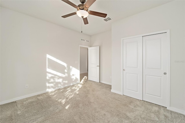 unfurnished bedroom with ceiling fan, light colored carpet, and a closet