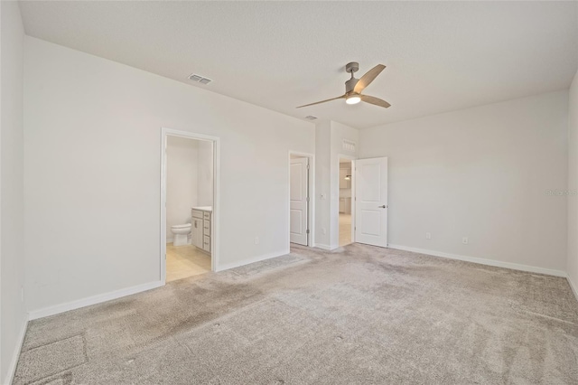 unfurnished bedroom with ceiling fan, ensuite bathroom, and light carpet